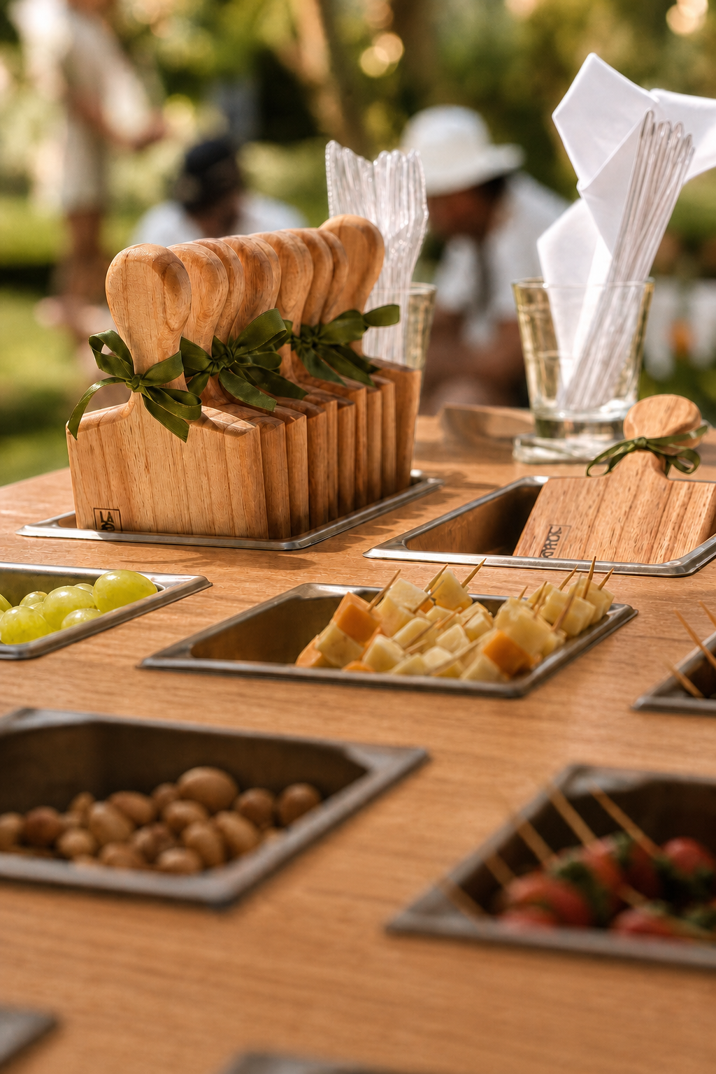 Detalhe do tampo do bar ao ar livre com tábuas de madeira com laços de folhagem, cubas de uvas, queijos, azeitonas e morangos