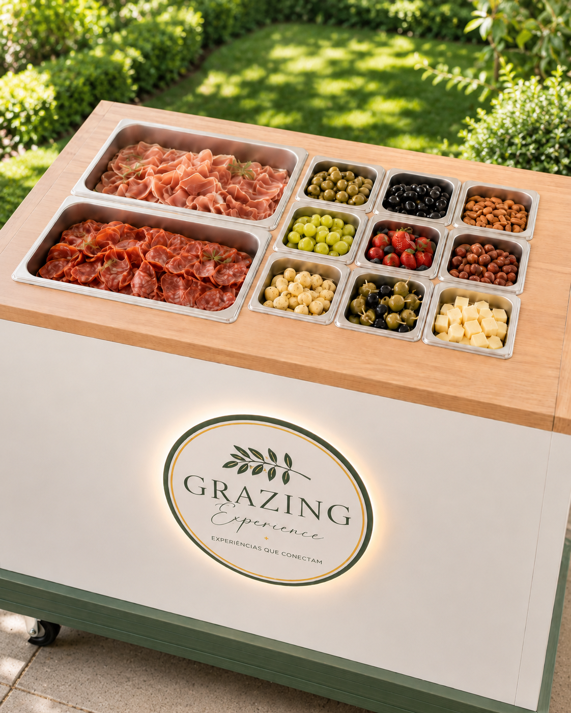 Vista superior do tampo do bar Grazing Experience com cubas de presunto cru, salame, azeitonas, uvas, nuts e queijos